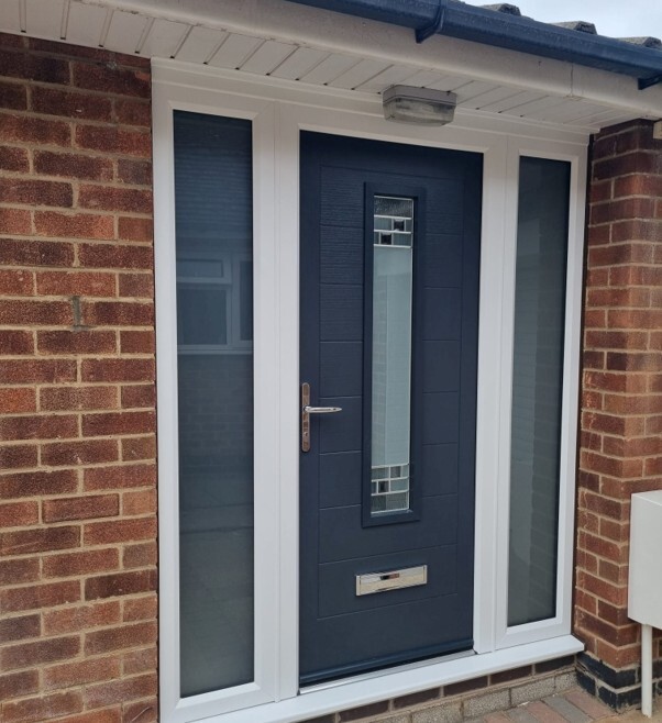 How much does a new composite front door cost? Modern composite front door with glazed side panels installed in a brick home.
